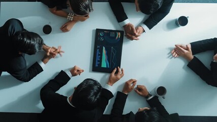 Top down aerial view of group of business people looking at financial chart while analyze and explain growing stock market statistic. Team placed tablet with chart at meeting table. Directorate.