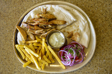 Dish with chicken pieces, French fries, wheat tortilla, onion and sauce. Top view. Copy space