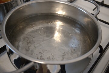 Hot water bubbling in a pot on the stove, photographed in a kitchen, close-up view.