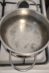 Hot water bubbling in a pot on the stove, photographed in a kitchen, close-up view.