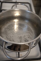 Hot water bubbling in a pot on the stove, photographed in a kitchen, close-up view.