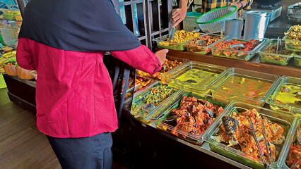 Indonesian street food stall with homemade dishes and customer selecting meal