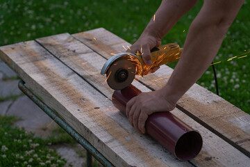 A man saws an iron pipe with a hand-held circular saw