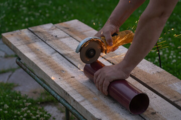 A man saws an iron pipe with a hand-held circular saw