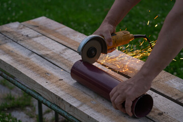 A man saws an iron pipe with a hand-held circular saw