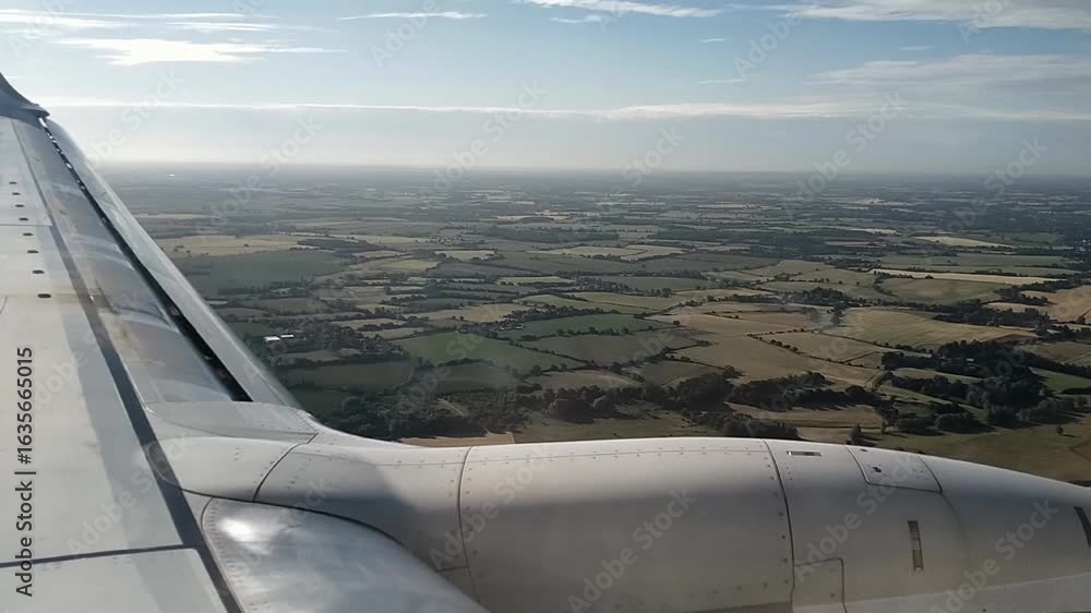 Poster pov shot from airplane window showing wing and aerial view of rural fields and farmlands during desc