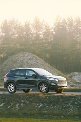 Modern crossover SUV driving near green field