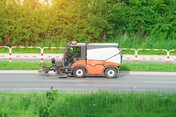 Street sweeper cleaning roadside on a sunny day