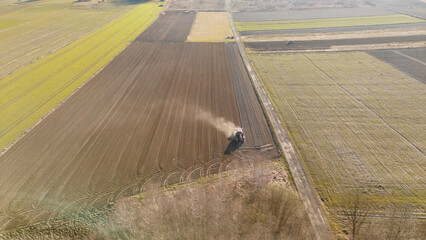 Aerial view of tractor plowing vast farmland