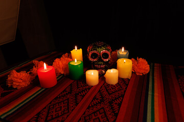 Black skull with colorful flowers and candles in a vibrant altar for Day of the Dead celebration