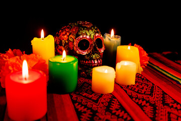 Traditional altar with black skull, colorful candles and magnolias for honoring Day of the Dead