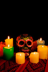 Colorful Day of the Dead altar with black skull, bright flowers and glowing candles