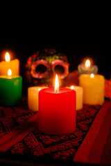 Floral-decorated black skull and burning candles used in Mexican Day of the Dead altars