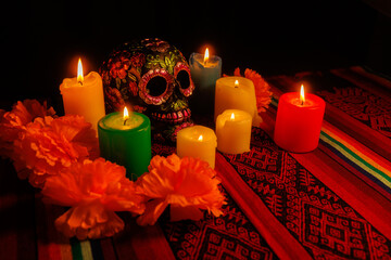 Painted skull in black with magnolia flower accents and bright wax candles for Día de Muertos