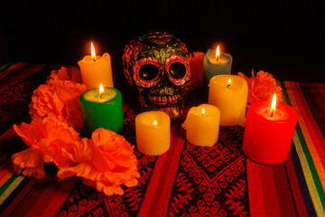 Day of the Dead altar display with symbolic skull, floral decor and vibrant colored candles