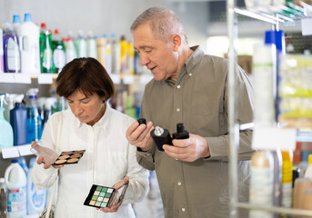 Couple elderly man and woman buyers choosing perfume and cosmetics in household chemicals store