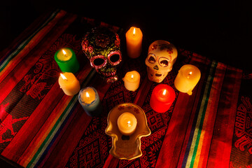 Honoring the dead with decorated ceramic skulls and candlelight in colorful traditional Día de...