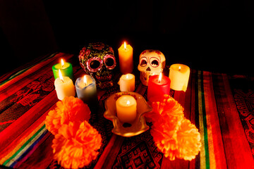 White and black skulls with candles and magnolia flowers on traditional altar for Day of the Dead