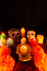 Day of the Dead altar with decorated skulls, glowing candles, and magnolias on a vibrant...