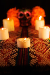 Festive altar with black skull, metal floral decorations, magnolias, and colorful candles for Day of the Dead
