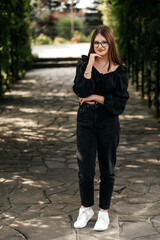 A girl in a park on a summer day, dressed in black, looking straight into the camera.