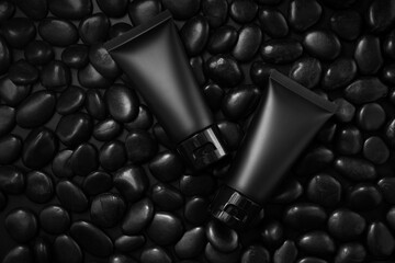 Black plastic cream tube with stone for mockup on black background. Selective Focus.