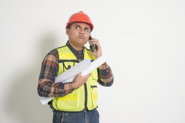 Asian construction worker wearing safety vest and helmet, holding project paper plans a phone,...
