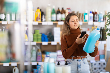 Young woman buyer scanning qr code for laundry detergent in household chemicals store