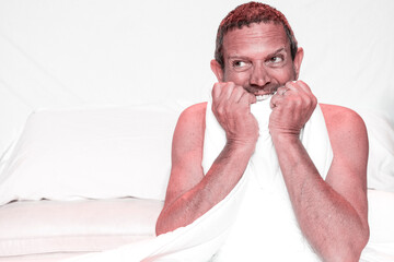 Man on bed, nervously biting towel as he prepares for a surprise event. Copy space.