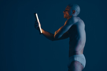 Confident man holding a light device, showcasing an artistic black and white composition. The focus...