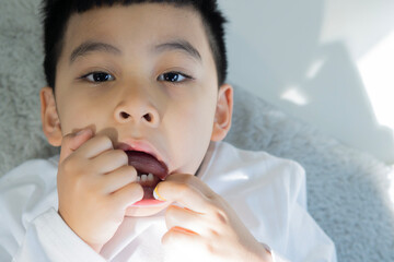 Portrait​ image​ of​ little boy​ 5​ years​ old lying on carpet while biting​ and​...