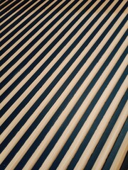 A wall with a diagonal pattern of dark stripes and light wooden slats, creating a repeating geometric texture