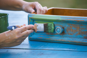 Painting a wooden furniture outdoors, an eco-friendly re-use business.