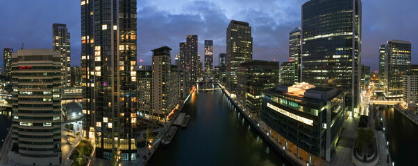 Naklejka premium London night cityscape panorama view. Canary wharf financial district business hub. Modern skyscraper architecture reflection water with building light