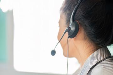 Remote Work. Female customer service representative using headset in modern office.