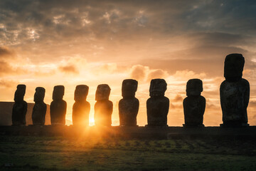 Sunrise at Ahu Tongariki, Rapa Nui (Easter Island), Chile, with silhouettes of colossal moai statues against orange sky. Tongariki is the largest ahu in Rapa Nui and counts 15 moai statues.