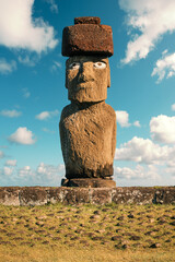 Front view of Ahu Ko Te Riku at the Tahai archaeological site, Rapa Nui (Easter Island), Chile, against blue sky. The moai has been completely restored, featuring eyes and a pukao topknot.
