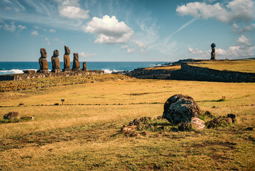 View of the Tahai ritual site on Rapa Nui (Easter Island), Chile, featuring Ahu Vai Uri with five moai statues and Ahu Ko Te Riku with a moai with eyes and a topknot. Moai remains in the foreground.