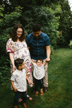 Hispanic family with pregnant mom and children laugh together