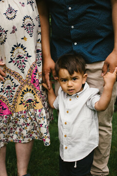 Latino toddler boy holds Dad hands together with his family