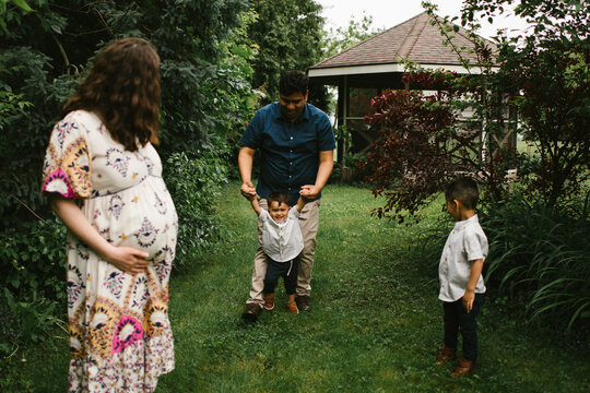 Hispanic family play together with father, pregnant mother and sons
