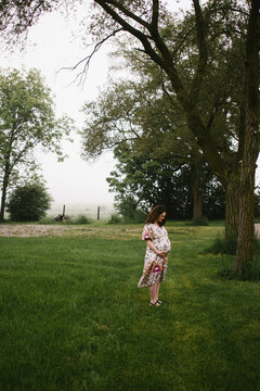 Mother expecting a baby happy in green field with trees
