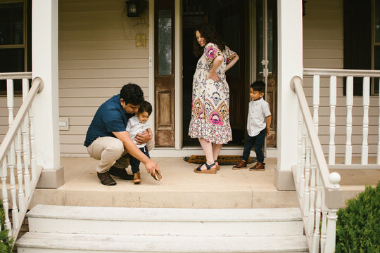 Hispanic family on front porch together with pregnant mother