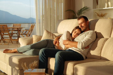 Obraz premium Couple in love resting on a couch at sunset at home