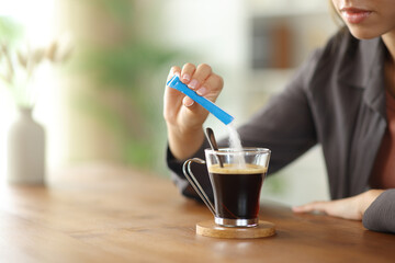 Woman hand throwing sugar in a coffee cup on a table at home