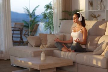 Yogi doing yoga listening audio from headphone at home