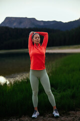 Athletic brunette stretching next to a lake
