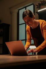 Office worker standing while finishing her work late at night