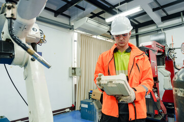 Engineer wearing safety uniform operating robotic machinery with control panel in smart...
