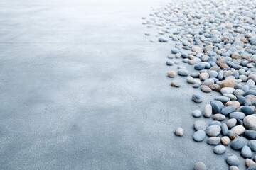 Obraz premium Smooth pebbles scattered on a textured concrete surface, creating a serene and calming atmosphere with natural elements and soft colors